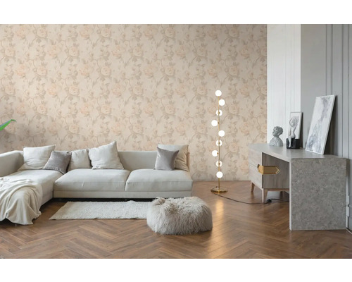 Obývací pokoj s květinovou tapetou se vzorem růží, světlá pohovka, dřevěná podlaha s rybinovým vzorem a moderní stojací lampa.
