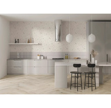 Světlá moderní kuchyně s květinovou tapetou, světlou dřevěnou podlahou rybí kost, bílými skříňkami, ostrůvkem, černými barovými stoličkami a svítidly.