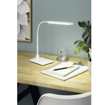 Psací stůl se stolní lampou, poznámkovým blokem, perem a sklenicí vody pro jasné a uspořádané pracovní prostředí.