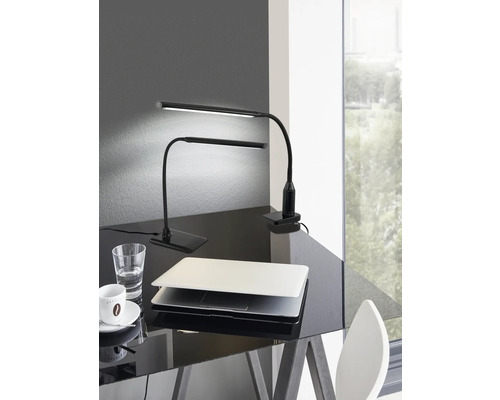 Dvě černé LED stolní lampy na lesklém stole s notebookem, sklenicí vody a šálkem kávy.