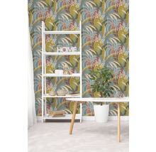 Vliesová tapeta s botanickým vzorem listů v zelené a hnědé barvě na modrém pozadí, bílá police a dřevěný stůl ve světlém pokoji.