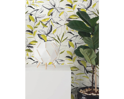 Moderní vliesová tapeta se žlutým a černým vzorem listů ve stylu skici za bílou lampou a pokojovou rostlinou.