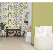 Svetlá předsíň s tapetou s motivem listů, zelenou barvou stěny, tmavým botníkem, bílým věšákem a světlým běhounem.