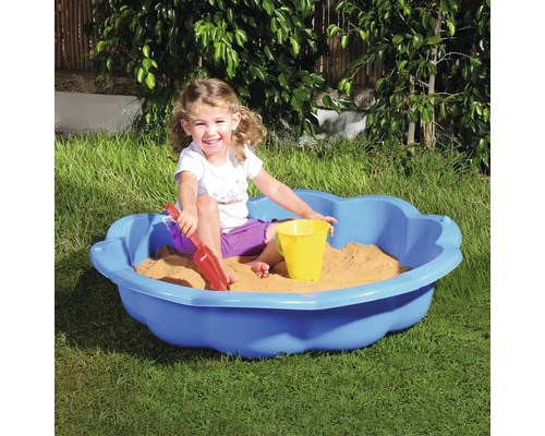 Dítě si hraje na zahradě v modrém pískovišti s hračkami do písku