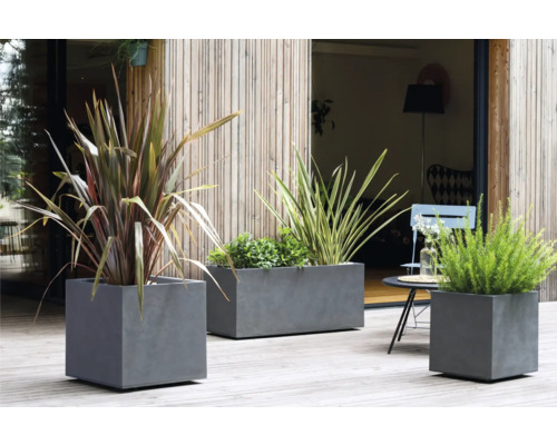 Tři šedé betonové květináče na terase s různými rostlinami