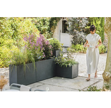 Zahradní pohled s šedými květináči a ženou nesoucí podnos