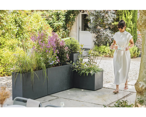 Zahradní pohled s šedými květináči a ženou nesoucí podnos