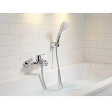 Koupelna s vanou, baterií a ruční sprchou před obkladačkami