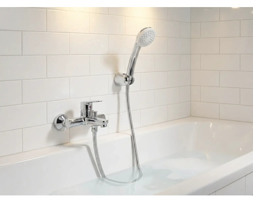 Koupelna s vanou, baterií a ruční sprchou před obkladačkami