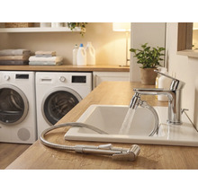 Světlá koupelna s umyvadlem, baterií se sprchovou hadicí a pračkami