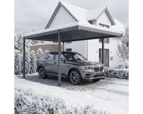 Auto stojí pod přístřeškem pro auto před domem v zimě.