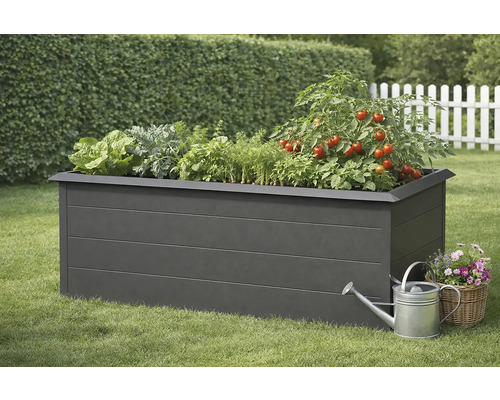 Zvýšený záhon se salátem, bylinkami a rostlinami rajčat, konev a košík s květinami na trávníku