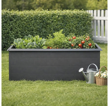 Zvýšený záhon se zeleninou, konví a košíkem s květinami na zahradě.