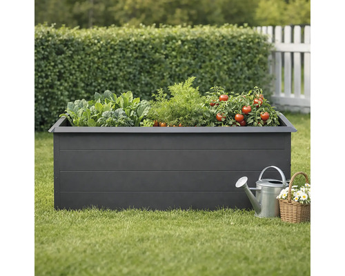 Zvýšený záhon se zeleninou, konví a košíkem s květinami na zahradě.