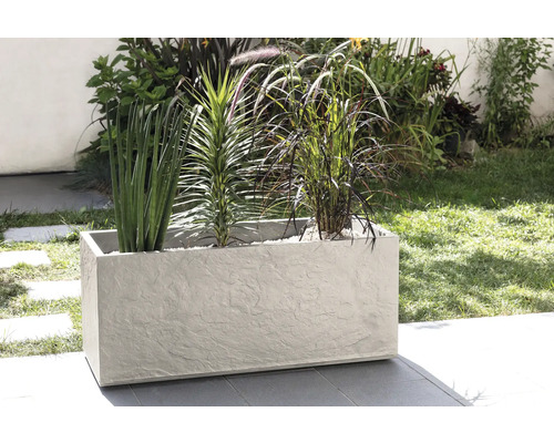 Obdélníkový květináč s různými rostlinami venku.