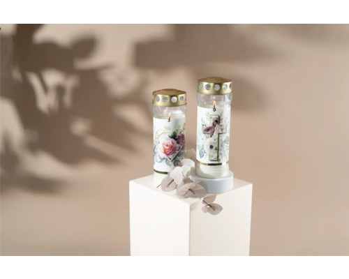Dvě hřbitovní svíčky s květinovými motivy na bílém podstavci.