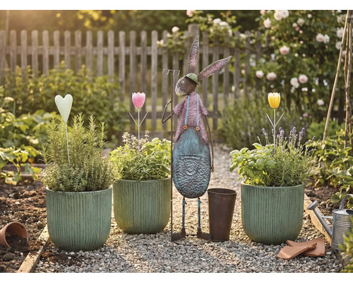 Zahradní scéna s osázenými květináči, kovovým zajícem a dekoracemi na štěrkové cestě