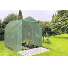 Zelený fóliový skleník s otevřenými dveřmi na dlážděné ploše v zahradě.