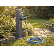 Zahradní scéna s vodovodním kohoutkem, rozdělovačem a zahradní hadicí na trávníku