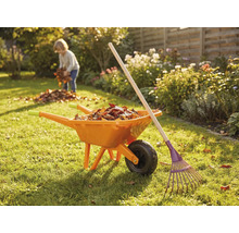 Zahradní scéna s kolečkem, hráběmi a dítětem sbírajícím listí