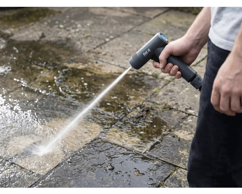 Osoba čistí kamenné desky venku pomocí akumulátorové vysokotlaké myčky.