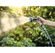 Ruka drží zahradní hadici s rozprašovací hlavicí