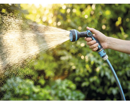 Ruka drží zahradní hadici s rozprašovací hlavicí