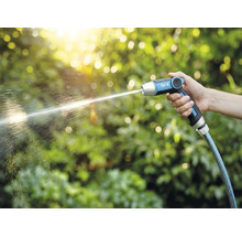 Ruka drží zahradní stříkací pistoli for_q, ze které tryská proud vody.