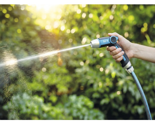 Ruka drží zahradní stříkací pistoli for_q, ze které tryská proud vody.