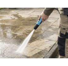 Osoba čistí kamennou terasu zahradní hadicí for_q