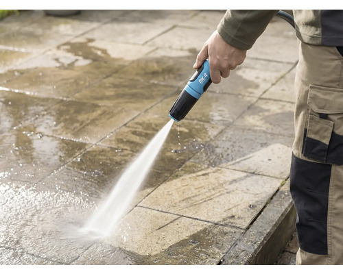 Osoba čistí kamennou terasu zahradní hadicí for_q