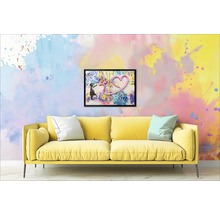 Žlutá pohovka s polštáři před zdí s orámovaným obrázkem dívky a srdce