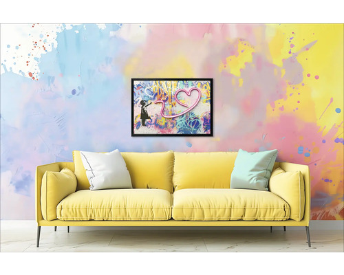 Žlutá pohovka s polštáři před zdí s orámovaným obrázkem dívky a srdce