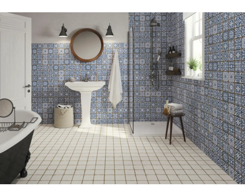 Koupelna se sprchou, umyvadlem, vanou a modrobílými vzorovanými obklady.