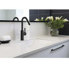 Umyvadlo s černou baterií, bílou pracovní deskou a dekorací v koupelně