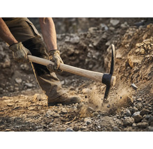 Muž používá krumpáč k kopání v zemi