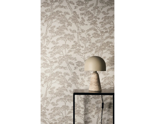 Vliesová tapeta s hnědým vzorem borovic na stěně za moderní stolní lampou na černém kovovém stolku.