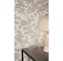 Světlý interiér s vliesovou tapetou s texturovaným vzorem borovic na stěně za stolem a stolní lampou.