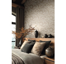 Tapeta se vzorem borovic v ložnici s dřevěným čelem postele, polštáři a vázami.