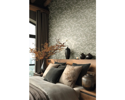 Vliesová tapeta se vzorem borovic v ložnici s dřevěným čelem postele, dekorativními polštáři a keramickými vázami s větvemi.