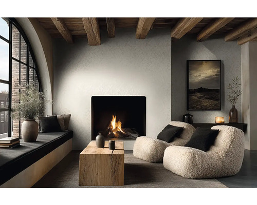 Moderní obývací pokoj s krbem, strukturovanými stěnami a dřevěnými trámy. Křesla, dřevěný stůl a útulné posezení u okna.