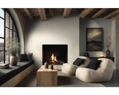 Útulný obývací pokoj s hořícím krbem, dvěma křesly z beránka, konferenčním stolkem z masivního dřeva a dřevěnými stropními trámy.