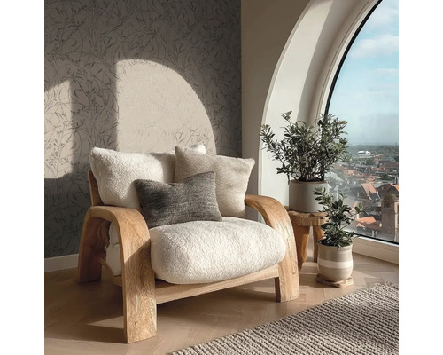 Světlé křeslo s polštáři vedle pokojových rostlin a okna