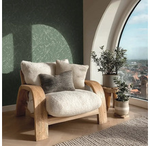 Světlá místnost s křeslem, polštáři, rostlinami a výhledem z okna