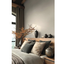 Ložnice s postelí, polštáři, vázami a dekorativními prvky pro klidnou atmosféru