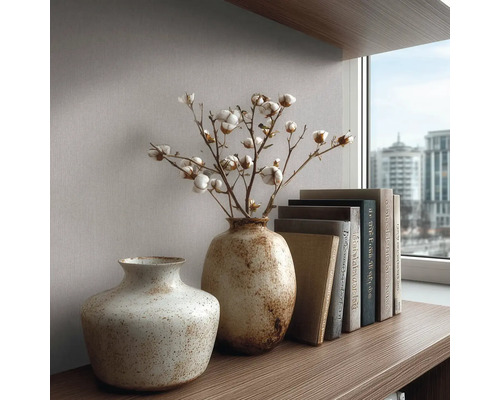 Strukturované keramické vázy s bavlněnými větvičkami a knihami na dřevěné polici před tapetou u okna.