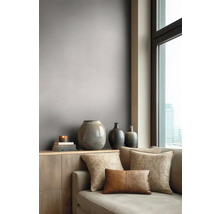 Moderní obývací pokoj s šedo-hnědou tapetou, pohovkou s dekoračními polštáři a vázami na komodě u okna.