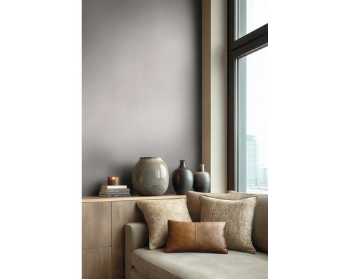 Moderní obývací pokoj s šedo-hnědou tapetou, pohovkou s dekoračními polštáři a vázami na komodě u okna.