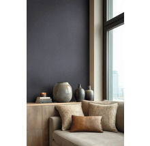 Moderní obývací pokoj s tmavou barvou stěny, dřevěnou komodou, keramickými vázami a pohovkou s texturovanými polštáři u okna s výhledem na město.