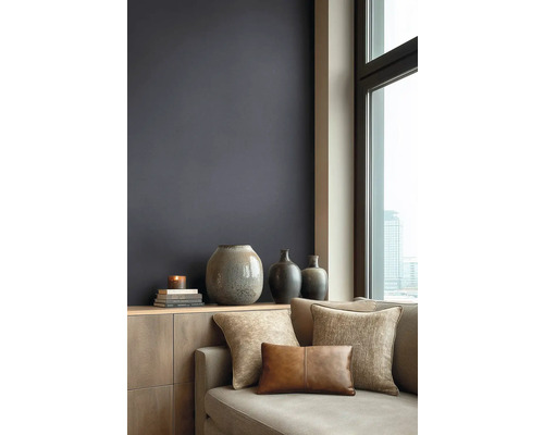 Moderní obývací pokoj s tmavou barvou stěny, dřevěnou komodou, keramickými vázami a pohovkou s texturovanými polštáři u okna s výhledem na město.